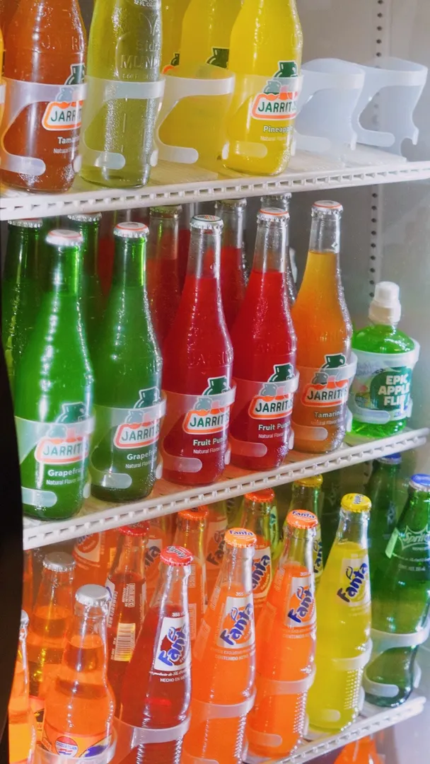 Colorful bottles of Mexican sodas displayed in the market refrigerator